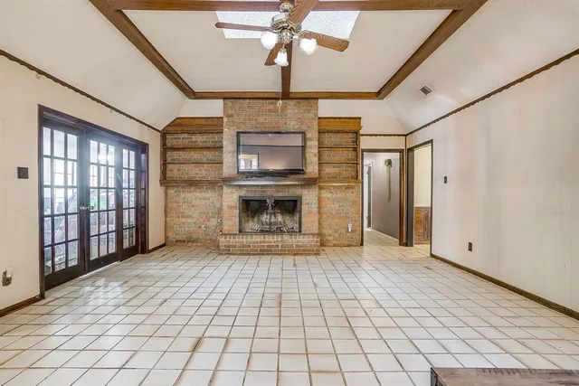 a view of an empty room with window and chandelier fan