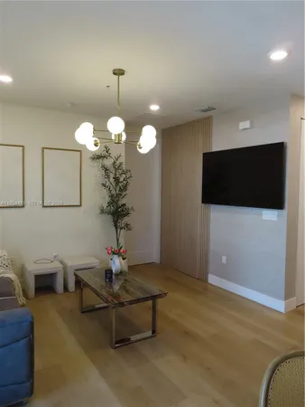 a living room with furniture a chandelier and a flat screen tv