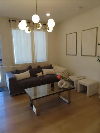 a living room with furniture a chandelier and a wooden floor