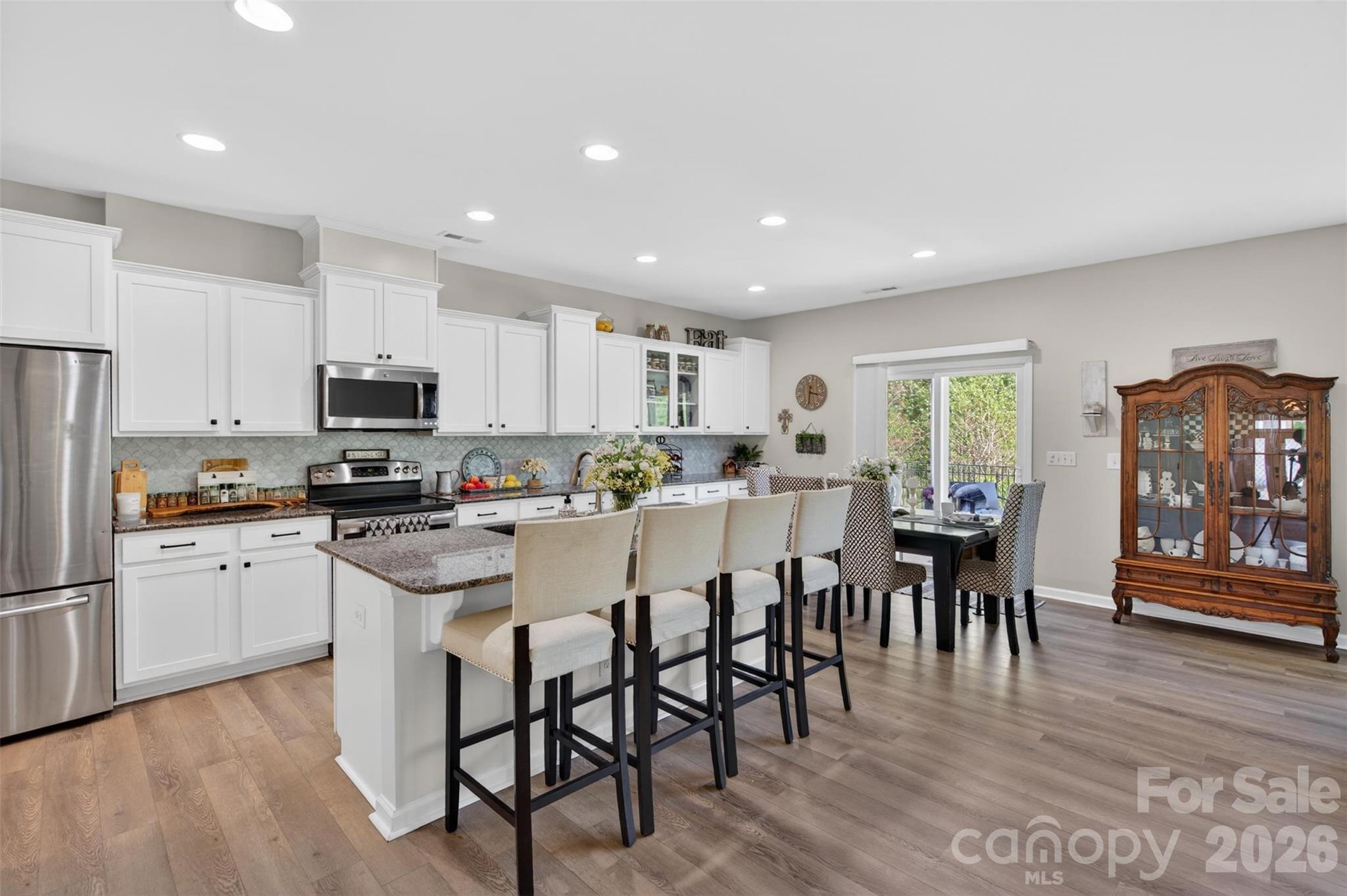 6038 Durango Way Denver, NC 28037 - Photo 7 of 20 a kitchen with stainless steel appliances granite countertop a refrigerator a stove top oven a dining table and chairs with wooden floor