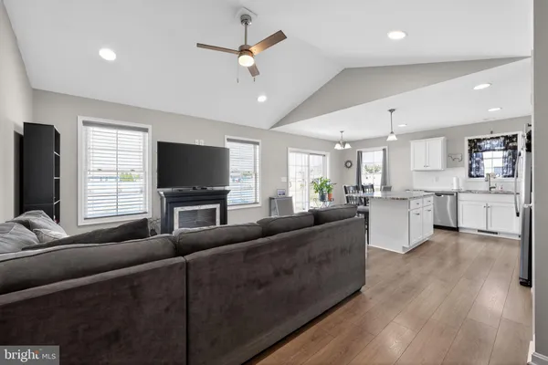 a living room with furniture kitchen view and a wooden floor