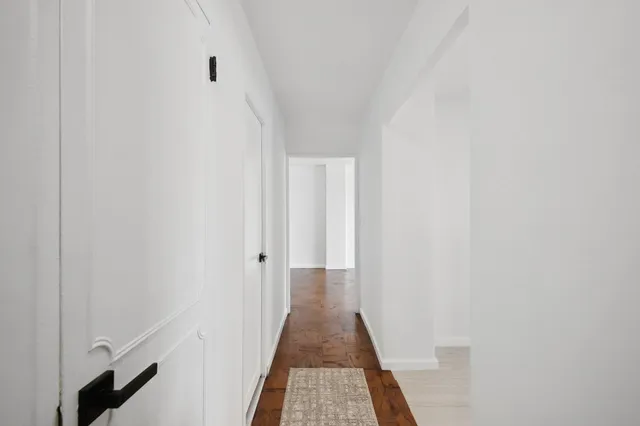 a view of a hallway with wooden floor and a bathroom
