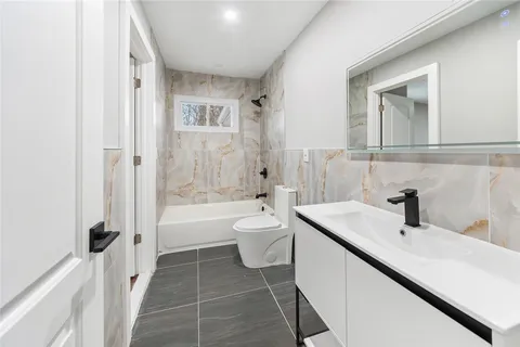 a bathroom with a double vanity sink toilet mirror and bathtub