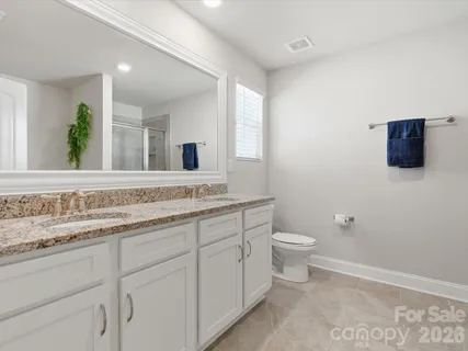 a bathroom with a granite countertop toilet sink and mirror