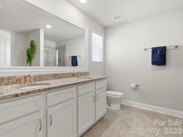 a bathroom with a granite countertop toilet sink and mirror