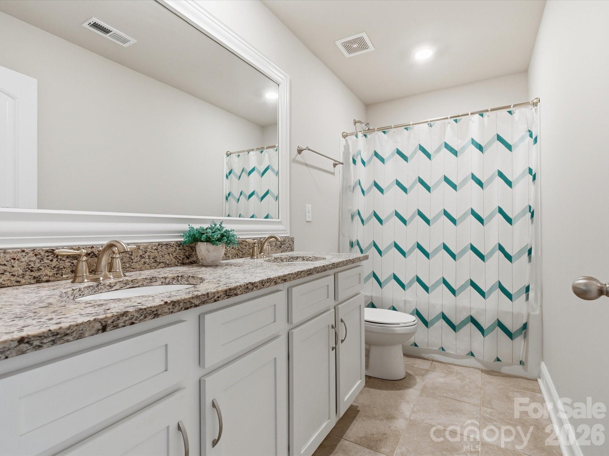4435 Allenby Place Monroe, NC 28110 - Photo 24 of 32 a bathroom with a granite countertop sink a toilet and a shower curtain