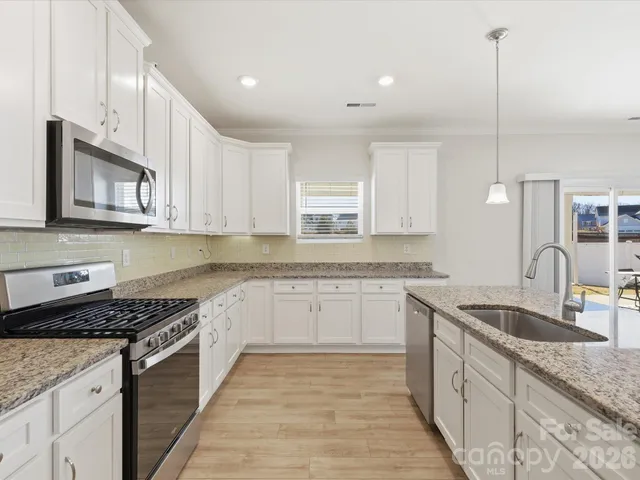 a kitchen with granite countertop cabinets stainless steel appliances a sink and a counter top space