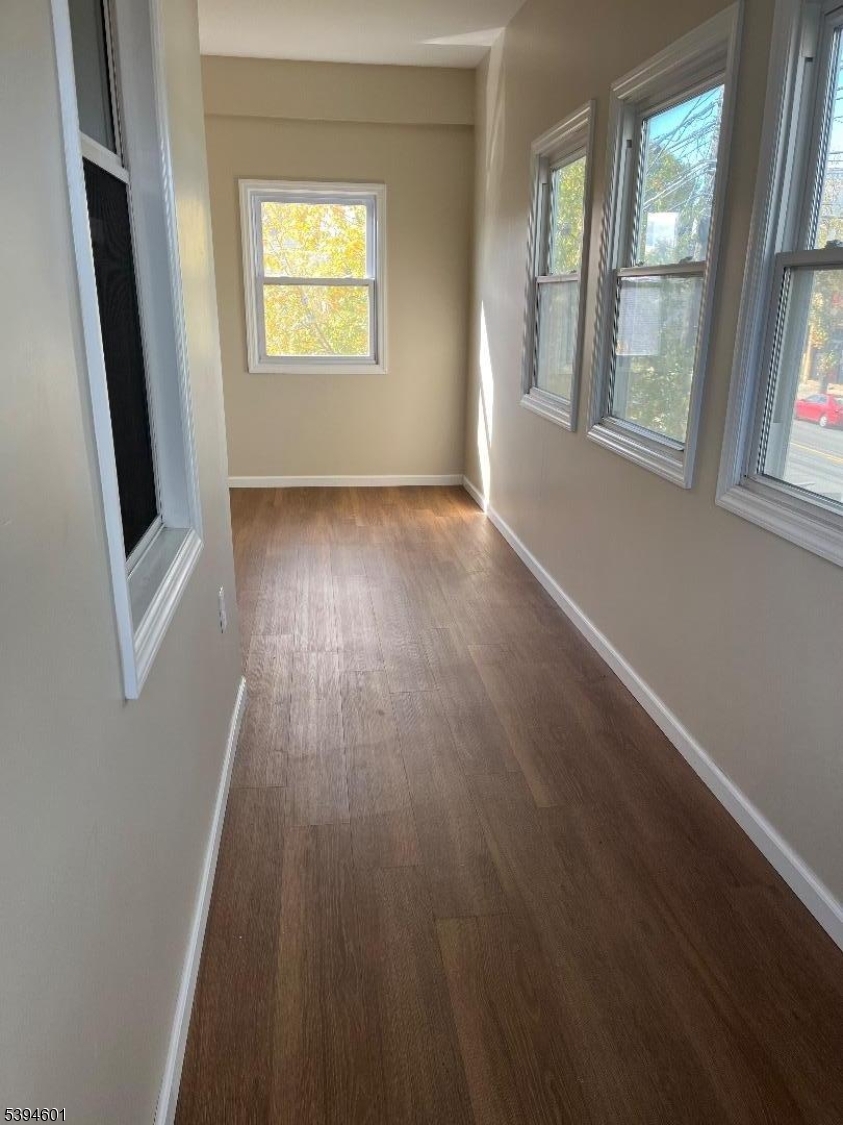 469 Crooks Avenue Clifton, NJ 07011 - Photo 3 of 12 an empty room with wooden floor and windows
