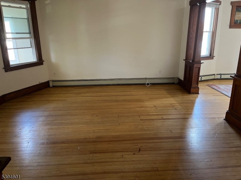 469 Crooks Avenue Clifton, NJ 07011 - Photo 5 of 12 an empty room with wooden floor and windows