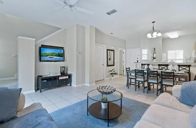 a living room with furniture kitchen view and a chandelier