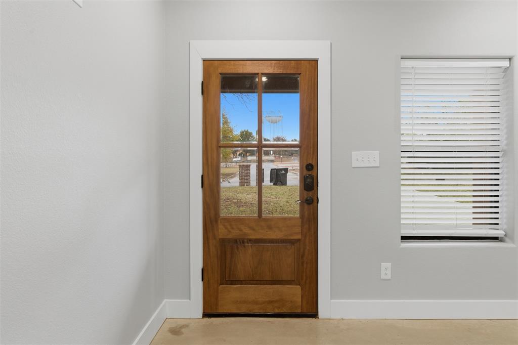 116 Harrison Street Denison, TX 75021 - Photo 10 of 25 Doorway to outside featuring baseboards and finished concrete flooring