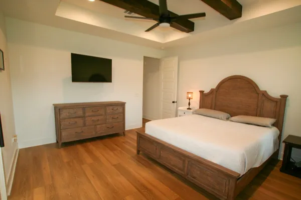 a bedroom with a bed a dresser and a flat screen tv