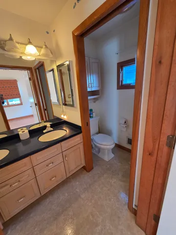 a bathroom with a granite countertop sink a toilet and a mirror