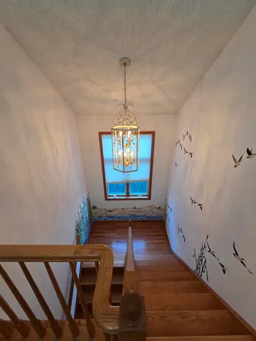 a view of a hallway with wooden floor and a chandelier