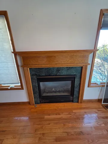 a view of an empty room with wooden floor fireplace and a window