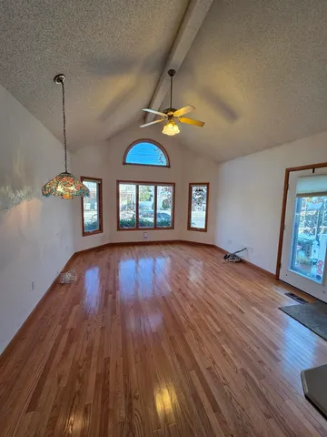 a view of empty room with wooden floor and fan