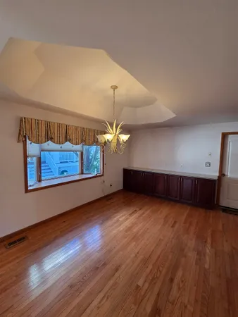 a view of an empty room with wooden floor fireplace and a window