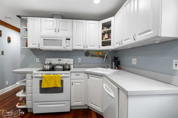 a kitchen with stainless steel appliances white cabinets and wooden floor