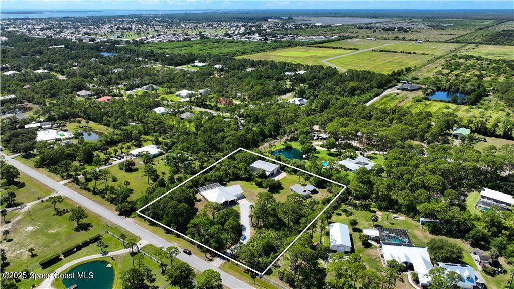 an aerial view of a residential houses with outdoor space and trees