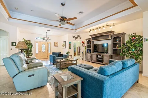 a living room with furniture a chandelier and a flat screen tv