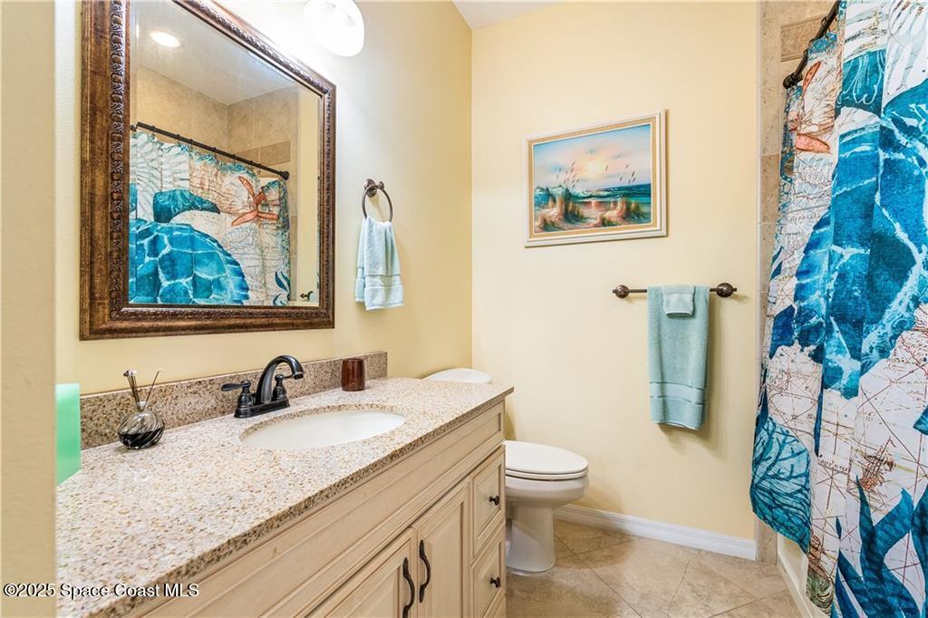 3975 Pepper Tree Street Grant, FL 32949 - Photo 20 of 36 a bathroom with a granite countertop toilet a sink and a mirror