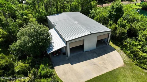 a aerial view of a house next to a yard with big trees