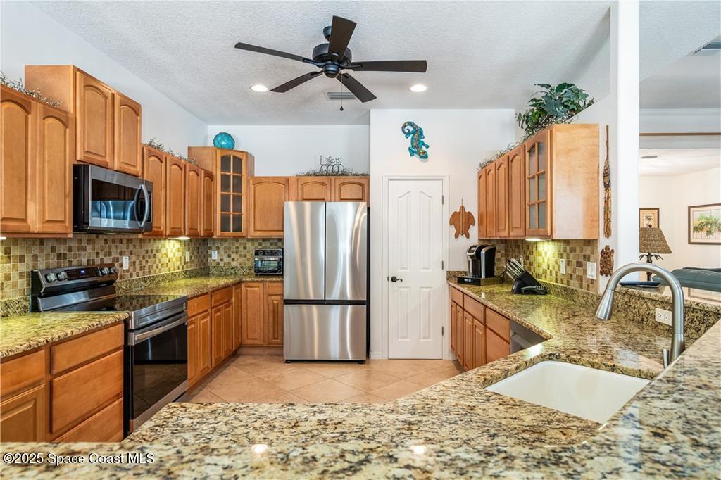 3975 Pepper Tree Street Grant, FL 32949 - Photo 7 of 36 a kitchen with stainless steel appliances granite countertop a sink refrigerator stove and microwave