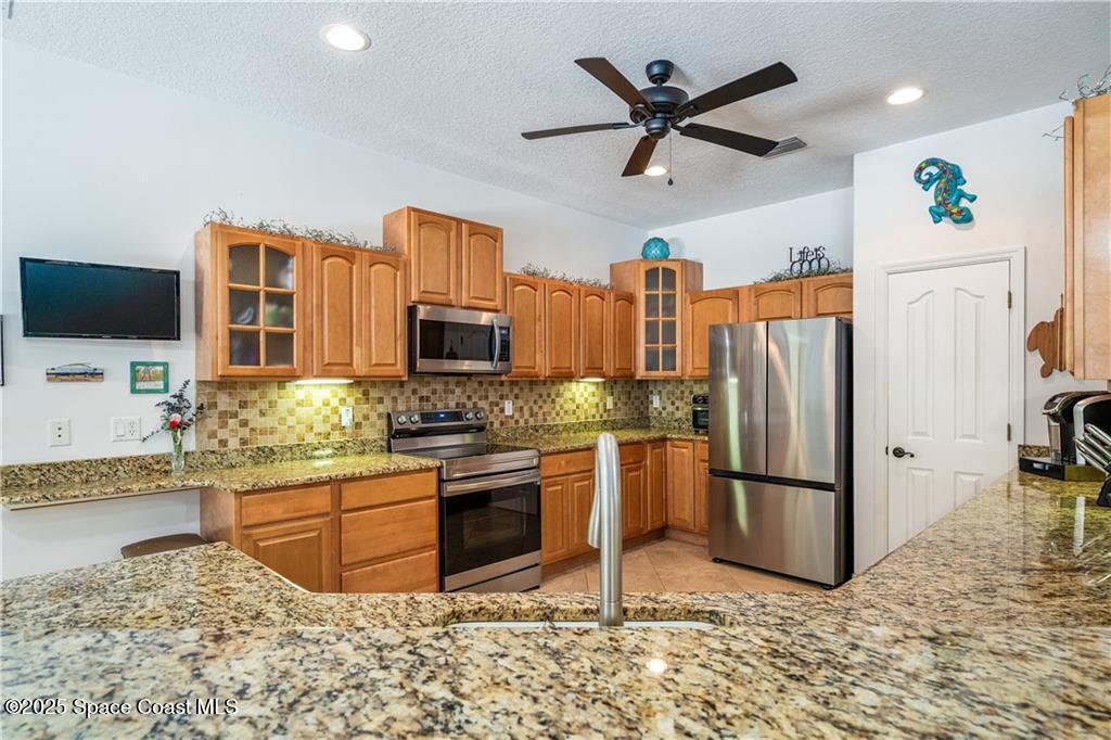 3975 Pepper Tree Street Grant, FL 32949 - Photo 8 of 36 a kitchen with stainless steel appliances granite countertop a refrigerator a stove a sink a oven with a dining table and chairs