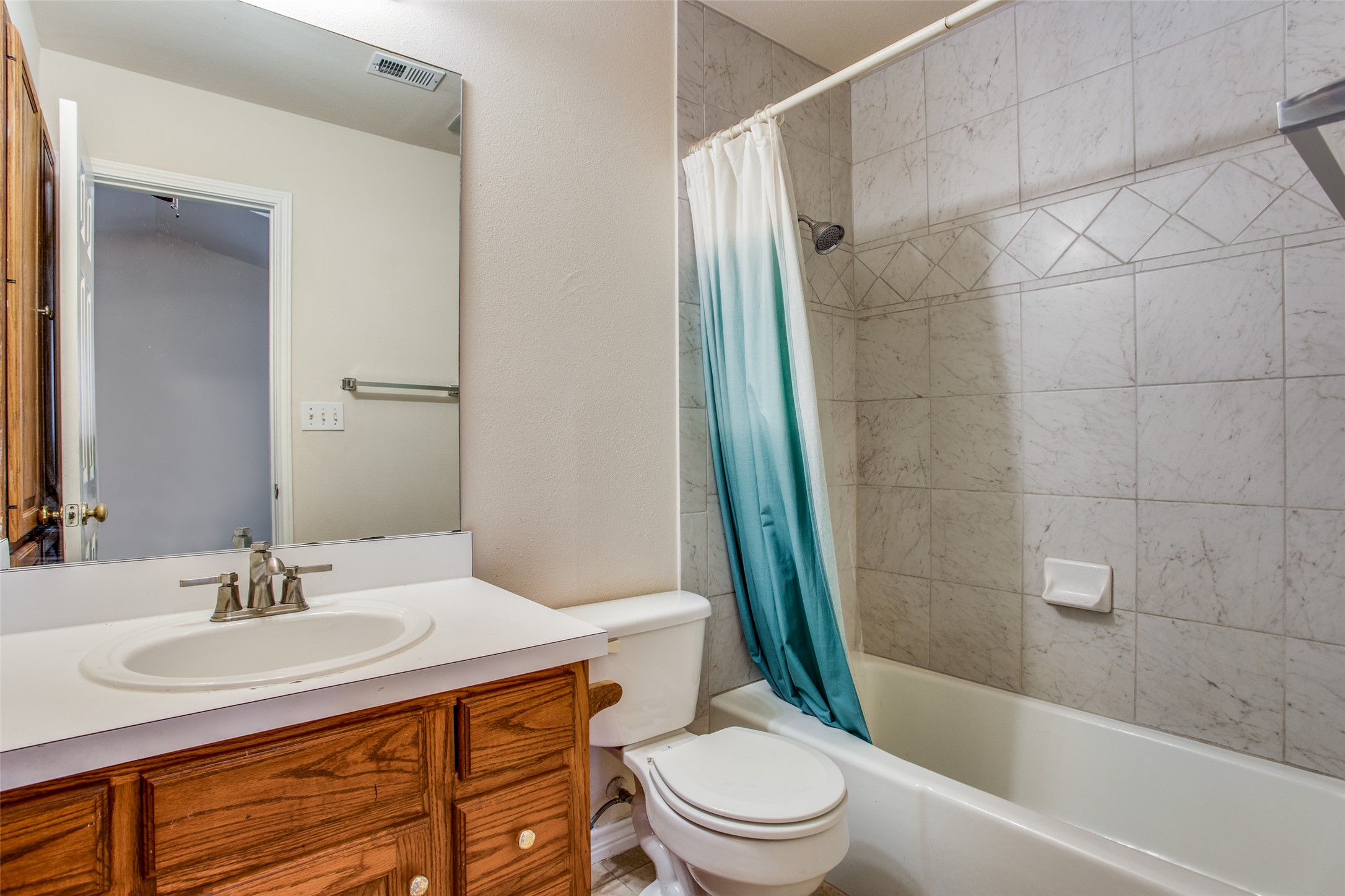8811 Clearbrook Trail Austin, TX 78729 - Photo 30 of 38 rt B - A well-lit bathroom provides a functional vanity with ample storage and a tiled shower-tub combination.