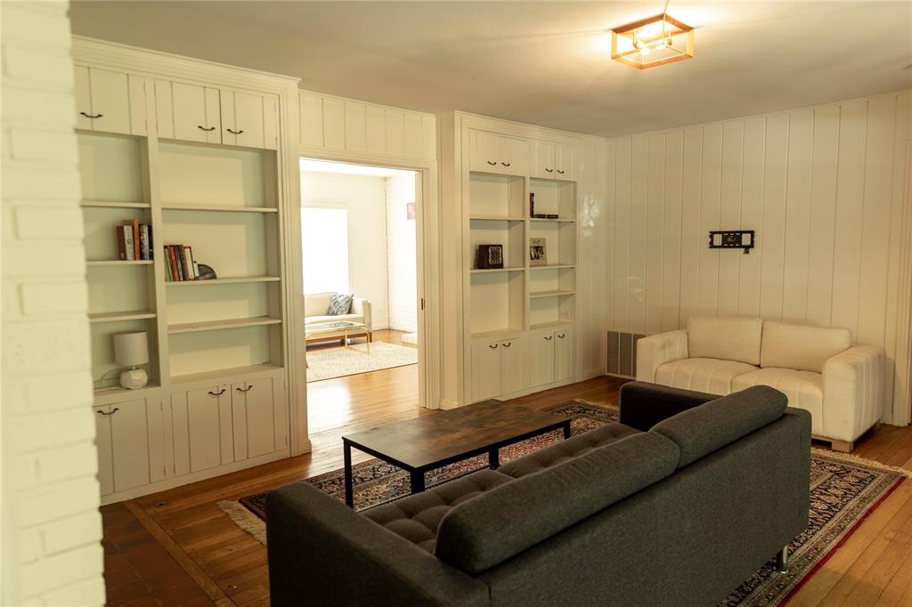 3228 Colcord Avenue Waco, TX 76707 - Photo 3 of 29 Living area featuring white paneled walls, built-in shelving with lower cabinetry, and wood-finish flooring