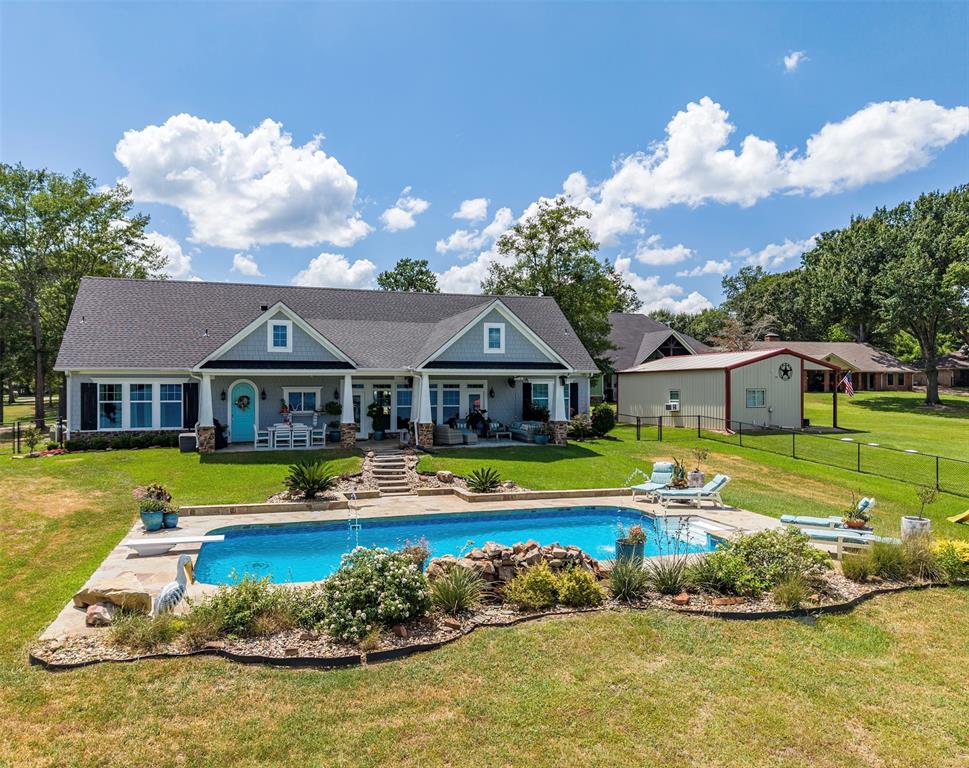16241 Big Oak Bay Road Tyler, TX 75707 - Photo 38 of 40 Rear exterior showcasing a large inground swimming pool with integrated rock features, an expansive concrete patio, and a diving board