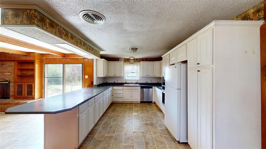 2309 Terrell Road Greenville, TX 75402 - Photo 14 of 30 a large white kitchen with a large window and stainless steel appliances