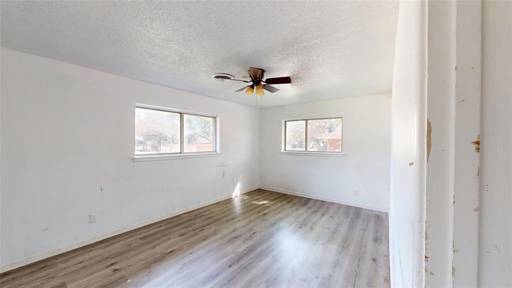 2309 Terrell Road Greenville, TX 75402 - Photo 25 of 30 an empty room with wooden floor ceiling fan and windows