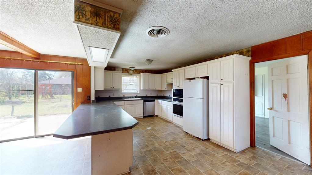 2309 Terrell Road Greenville, TX 75402 - Photo 10 of 30 a kitchen with a refrigerator a stove and a sink with wooden floor