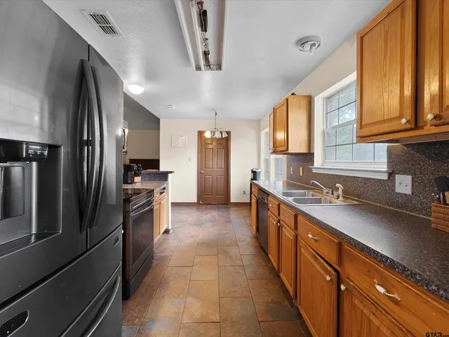 a large kitchen with stainless steel appliances granite countertop a refrigerator and a sink