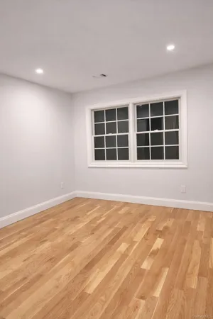 a view of an empty room with a window and wooden floor