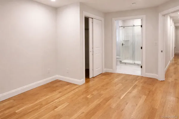 a view of an empty room with wooden floor and a bathroom