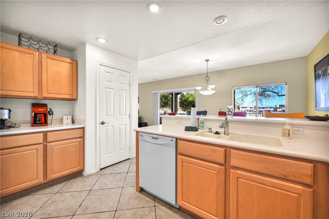10730 Amber Ridge Drive, Unit 101 Las Vegas, NV 89144 - Photo 15 of 32 A well-lit kitchen with natural wood cabinets, ample counter space, and a clear view to the outdoors.