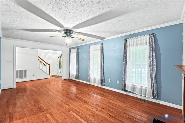 a view of an empty room with a window and a chandelier fan