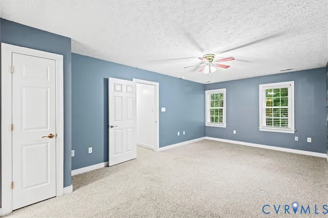 an empty room with chandelier fan and windows