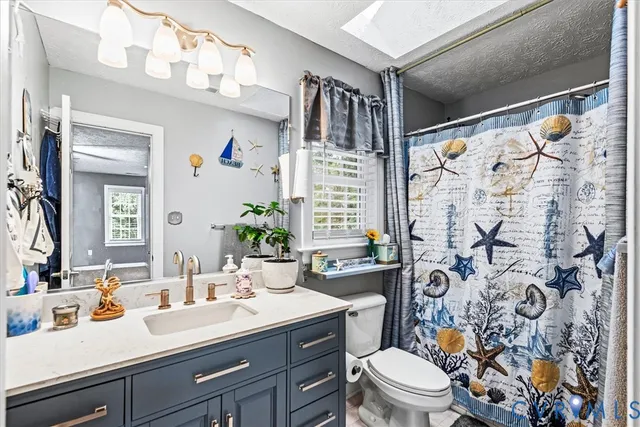 a bathroom with a sink a toilet and shower curtain