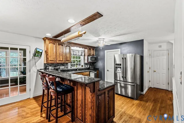 a kitchen with stainless steel appliances granite countertop a refrigerator a stove and a wooden cabinets
