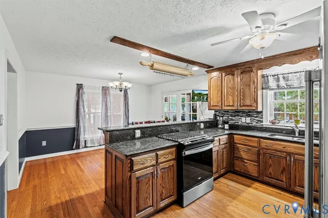 a kitchen with stainless steel appliances granite countertop a sink a stove and a wooden cabinets