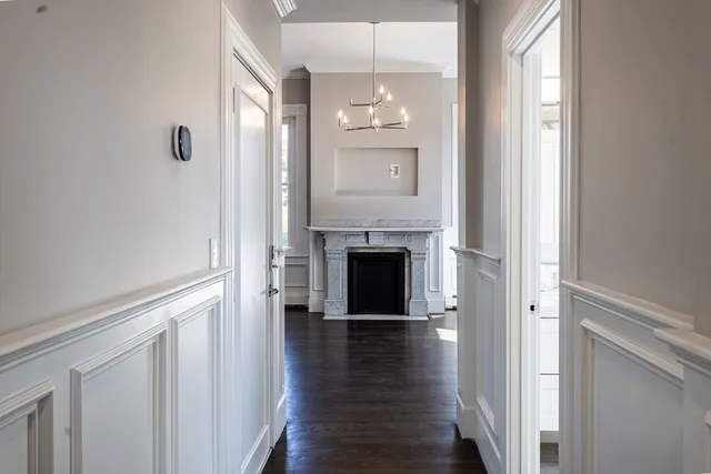 a view of a hallway with wooden floor and a bathroom