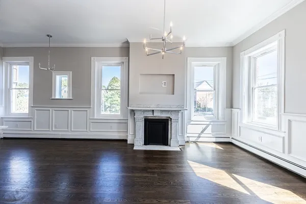 an empty room with wooden floor fireplace and windows