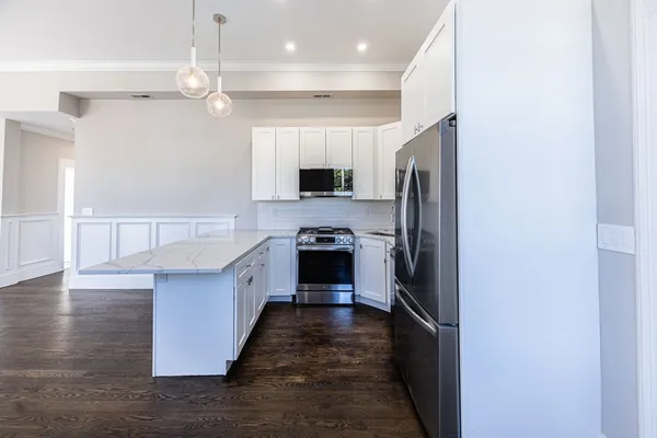 a large kitchen with stainless steel appliances a refrigerator and a stove top oven