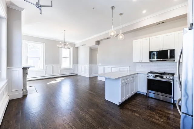 a large kitchen with stainless steel appliances granite countertop a stove and a wooden floors