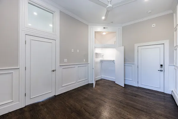 an empty room with wooden floor & cabinet and mirrors