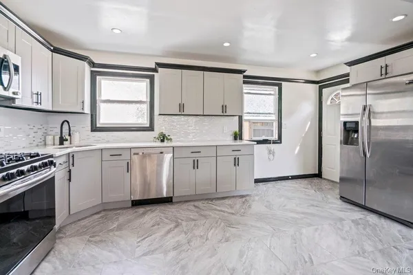 a kitchen with white cabinets stainless steel appliances and a window