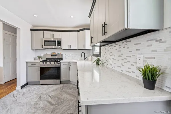a kitchen with stainless steel appliances a stove a sink a microwave a refrigerator and cabinets